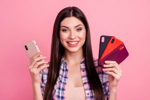 Młoda kobieta trzymająca w rękach różne etui na telefon